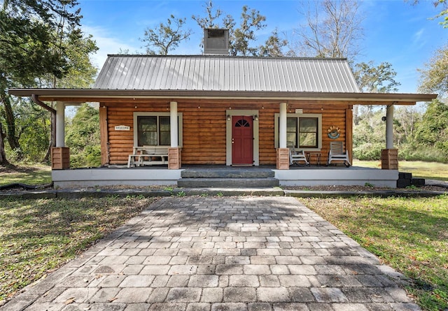 view of front facade with metal roof, a porch, and a chimney