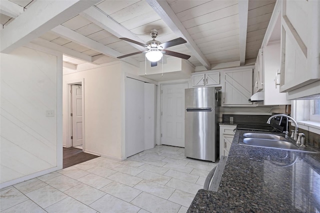 kitchen featuring ventilation hood, beamed ceiling, freestanding refrigerator, white cabinetry, and a sink