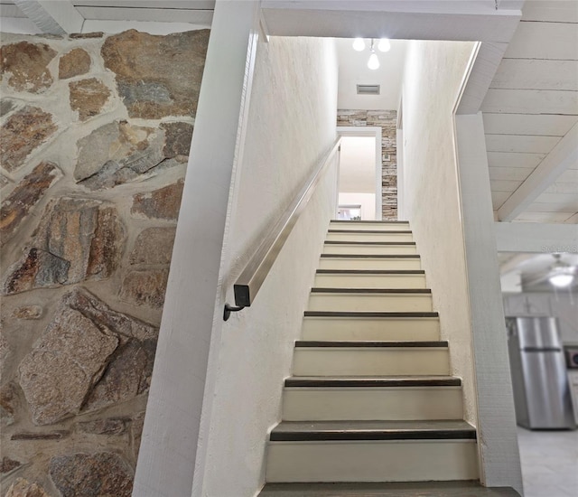 stairway featuring beam ceiling and visible vents