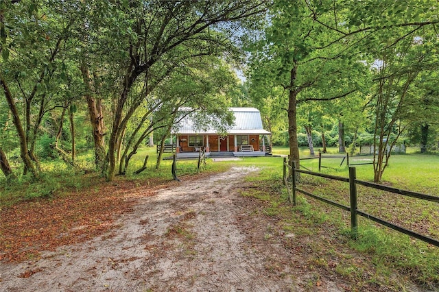 view of front facade with a front lawn, fence, covered porch, and dirt driveway