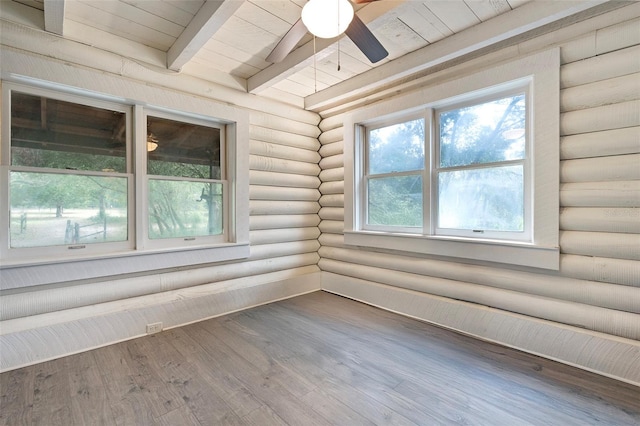 empty room featuring beamed ceiling, a ceiling fan, wood finished floors, rustic walls, and wood ceiling