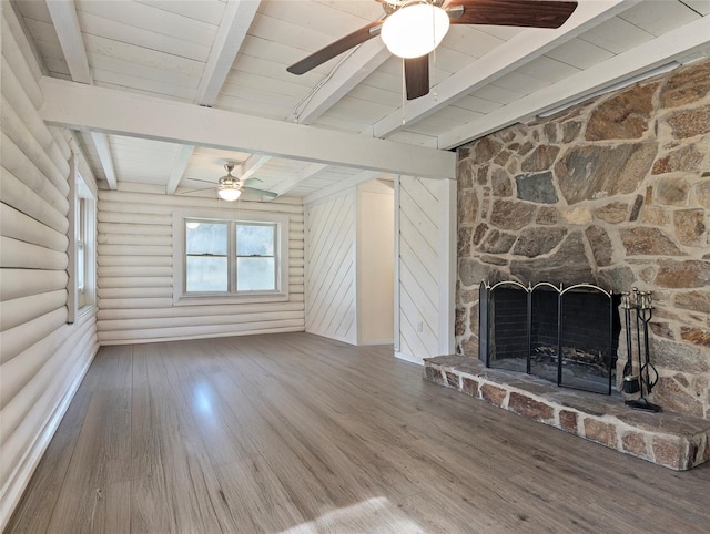 unfurnished living room with wood finished floors, log walls, a stone fireplace, wood ceiling, and beamed ceiling