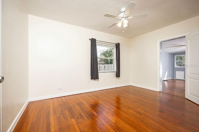 spare room featuring a healthy amount of sunlight, wood-type flooring, and baseboards