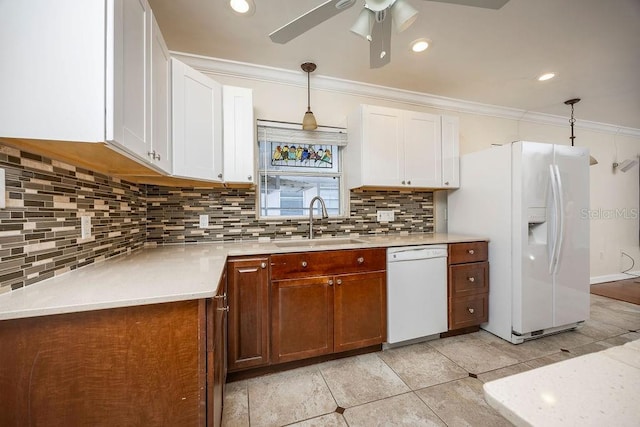 kitchen with white appliances, a sink, light countertops, tasteful backsplash, and crown molding