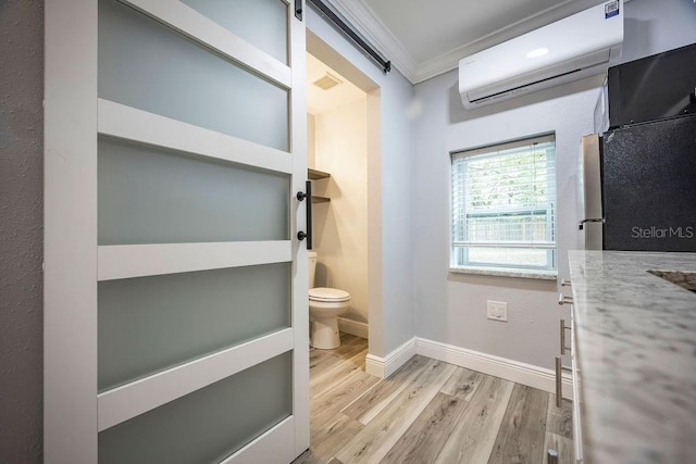 bathroom featuring baseboards, toilet, wood finished floors, crown molding, and a wall mounted AC