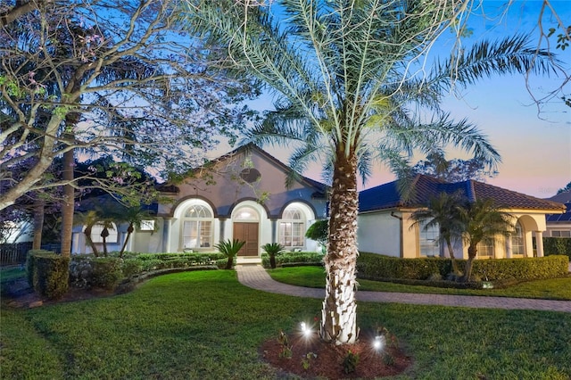 mediterranean / spanish-style house with stucco siding and a yard