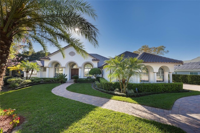 mediterranean / spanish-style home featuring stucco siding, a front yard, and a tile roof