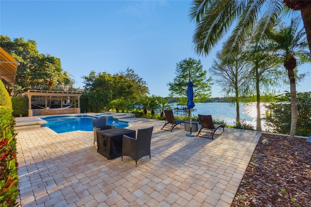 view of pool featuring a patio, a water view, and a pool with connected hot tub