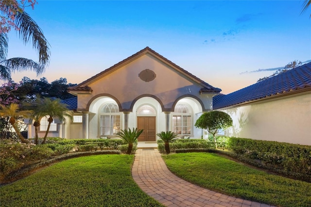 view of front of property featuring stucco siding and a yard