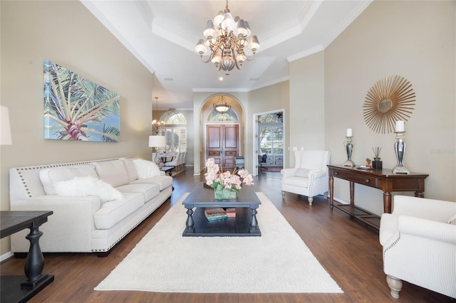 living area featuring a chandelier, dark wood finished floors, crown molding, and a raised ceiling