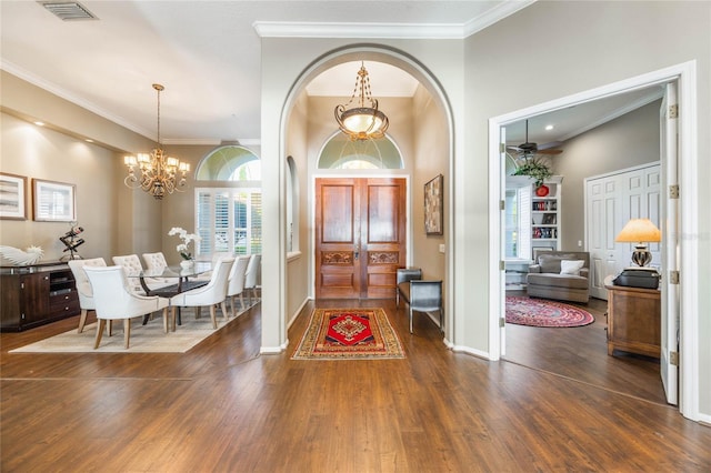 foyer entrance with visible vents, crown molding, baseboards, an inviting chandelier, and wood finished floors