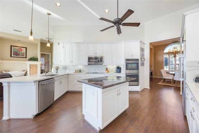 kitchen featuring ornamental molding, decorative backsplash, appliances with stainless steel finishes, a peninsula, and a sink