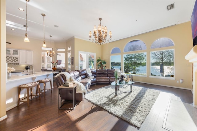 living room with visible vents, baseboards, dark wood-type flooring, crown molding, and a chandelier