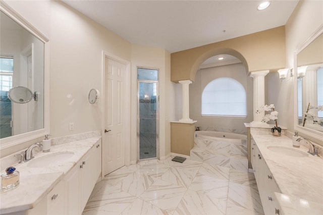 bathroom featuring a shower stall, a garden tub, ornate columns, and a sink