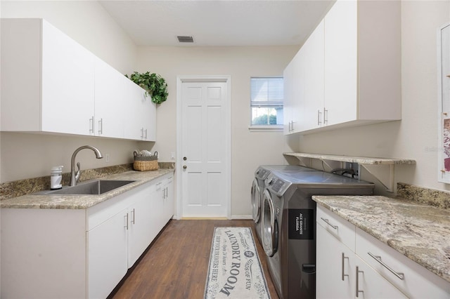 laundry area with washing machine and clothes dryer, visible vents, a sink, cabinet space, and dark wood-style flooring