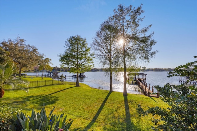 view of yard featuring a water view, a boat dock, and fence