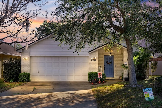 view of front of home with a garage, concrete driveway, and brick siding