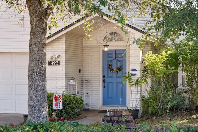 view of exterior entry featuring brick siding and an attached garage