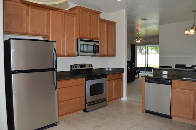 kitchen featuring dark stone counters, appliances with stainless steel finishes, a textured ceiling, a sink, and ceiling fan with notable chandelier