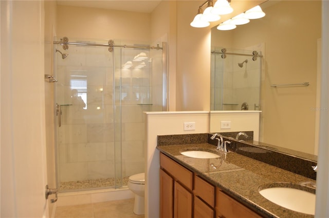 bathroom featuring double vanity, a sink, toilet, and a shower stall