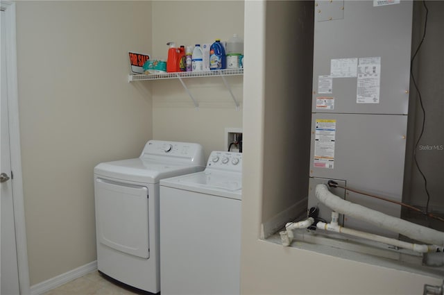 laundry room with heating unit, washing machine and dryer, light tile patterned flooring, laundry area, and baseboards