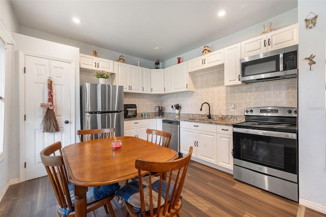 kitchen with stainless steel appliances, dark wood-type flooring, a sink, and white cabinetry