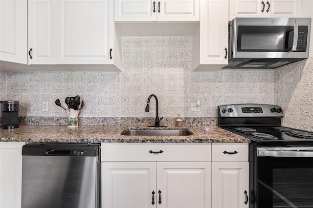 kitchen with stone counters, tasteful backsplash, appliances with stainless steel finishes, white cabinets, and a sink