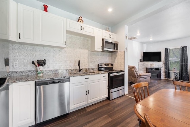 kitchen featuring visible vents, dark wood-style floors, appliances with stainless steel finishes, light stone countertops, and a sink