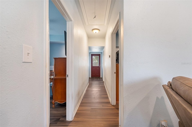 hallway featuring attic access, baseboards, and wood finished floors