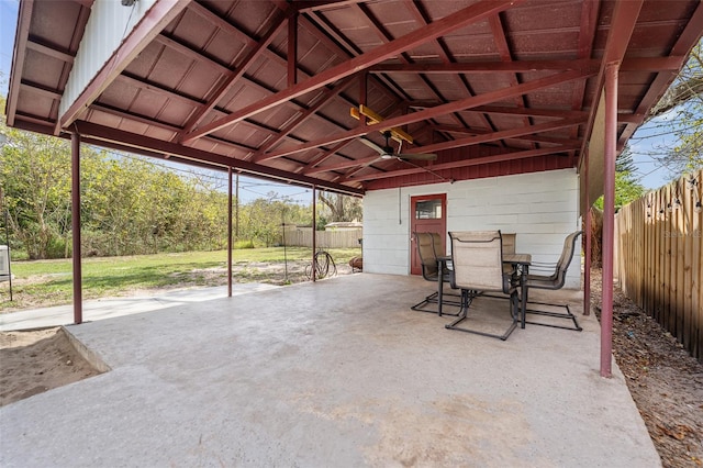 view of patio featuring a carport, outdoor dining area, fence, and a ceiling fan