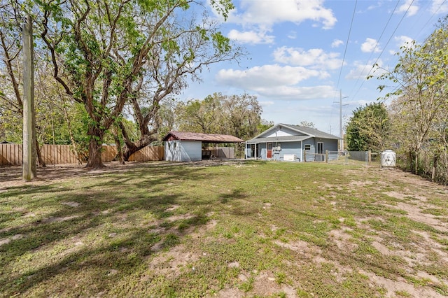 view of yard featuring a fenced backyard, a storage unit, a carport, and an outdoor structure