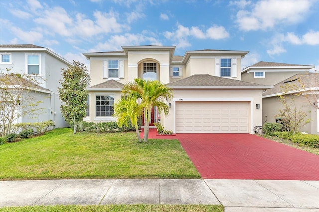 view of front of home featuring decorative driveway, a front yard, an attached garage, and stucco siding