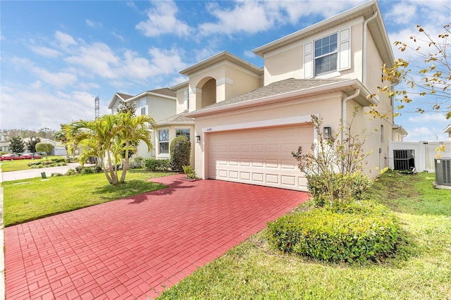 view of front facade featuring stucco siding, a front lawn, decorative driveway, central AC, and a garage