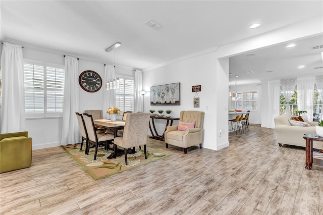 dining space with a healthy amount of sunlight, wood finished floors, and ornamental molding