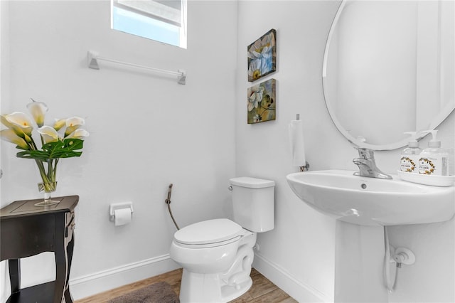 half bath featuring toilet, wood finished floors, and baseboards