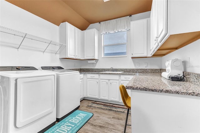 washroom featuring a sink, cabinet space, light wood finished floors, and washer and clothes dryer