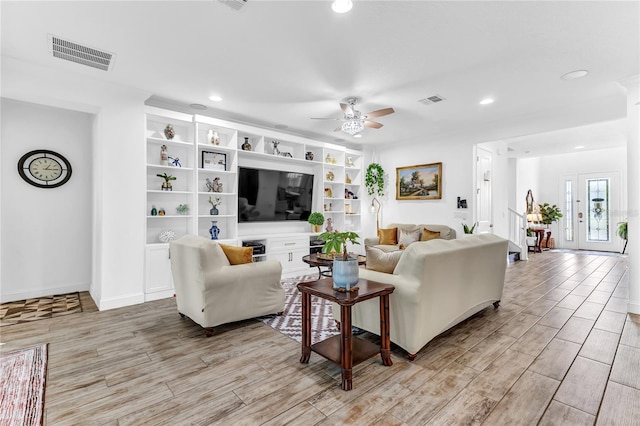 living room with a ceiling fan, light wood-style floors, and visible vents