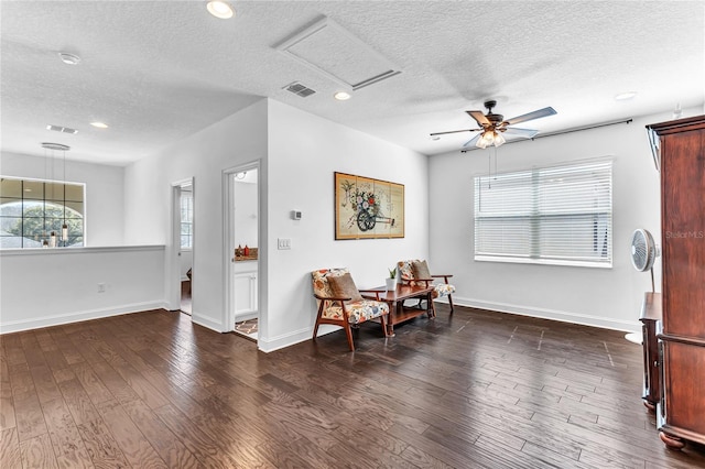 living area featuring visible vents, baseboards, attic access, and wood finished floors