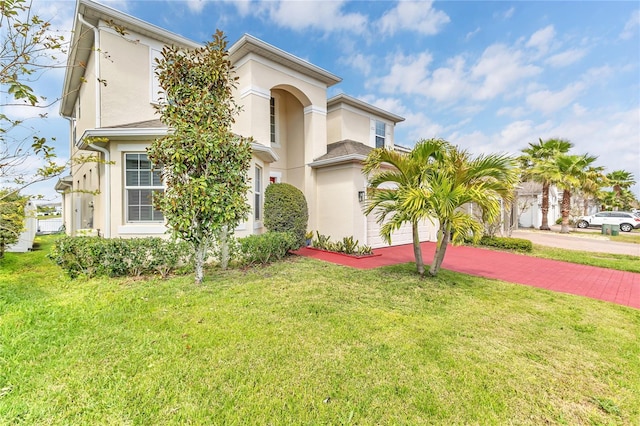 mediterranean / spanish-style home with stucco siding, decorative driveway, and a front yard