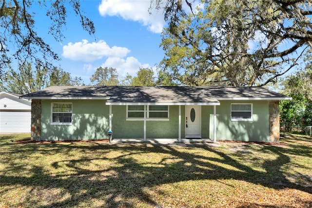 ranch-style home featuring an outbuilding, a front lawn, and stucco siding