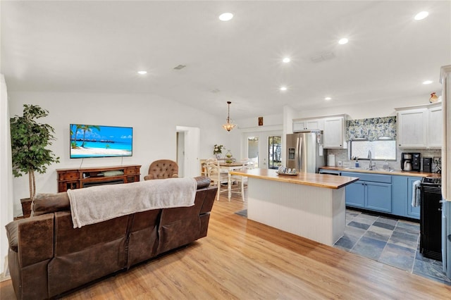 kitchen with open floor plan, a kitchen island, stainless steel refrigerator with ice dispenser, and wood finished floors