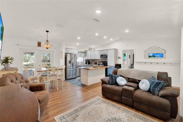 living area featuring visible vents, an inviting chandelier, vaulted ceiling, light wood-style floors, and recessed lighting