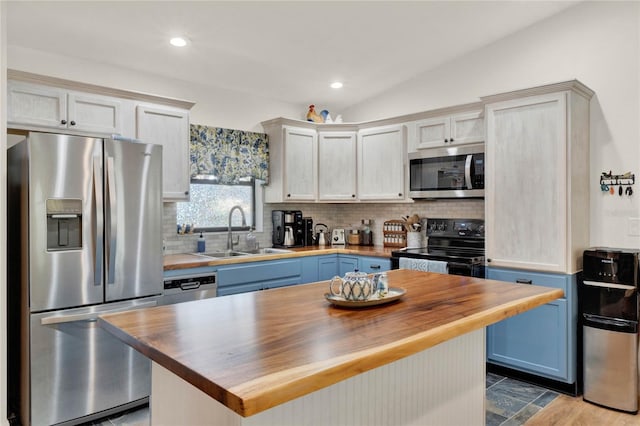 kitchen featuring lofted ceiling, butcher block counters, a sink, stainless steel appliances, and backsplash