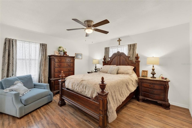 bedroom with ceiling fan, wood finished floors, and baseboards