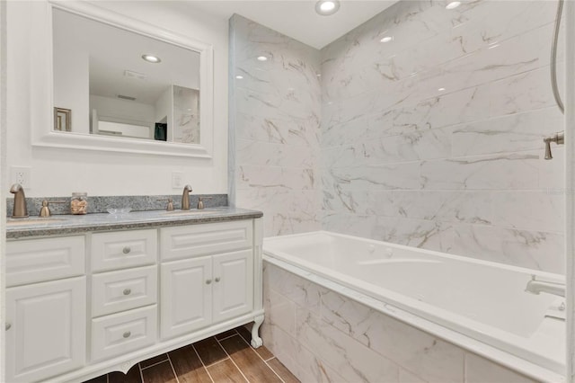 full bathroom featuring recessed lighting, a sink, wood tiled floor, double vanity, and a tub with marble appearance