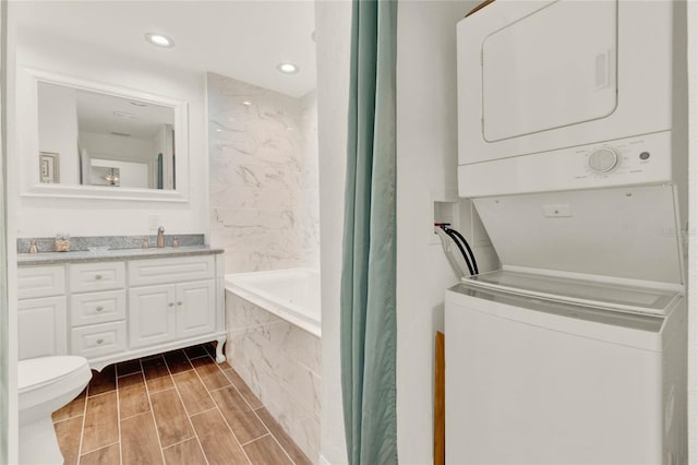 full bathroom featuring shower / bath combination with curtain, toilet, stacked washer / dryer, wood tiled floor, and vanity