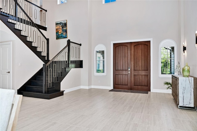 entryway with baseboards, a high ceiling, stairway, and a healthy amount of sunlight