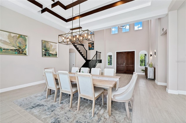 dining area featuring arched walkways, a notable chandelier, a raised ceiling, stairway, and baseboards