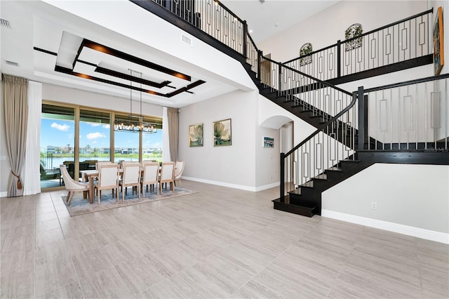 dining space featuring an inviting chandelier, baseboards, stairway, and a raised ceiling