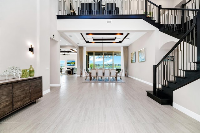 entrance foyer with a raised ceiling, baseboards, stairway, and a high ceiling